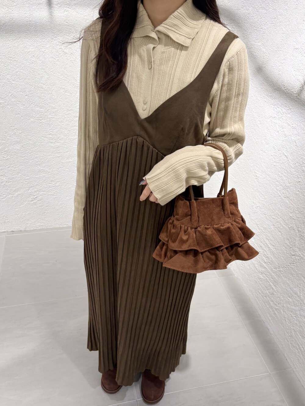 ブラウン系のワンピース、ベージュ系のニット/セーター、ブラック系のデニムパンツを着用したレディースの冬コーディネートの3枚目の写真