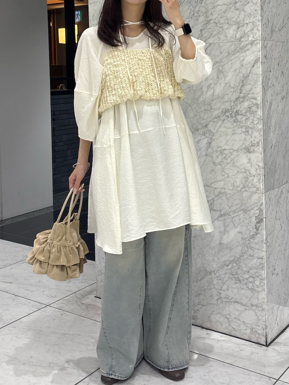 ホワイト系のワンピース、ホワイト系のニット/セーター、ブルー系のデニムパンツを着用したレディースの春コーディネートの3枚目の写真