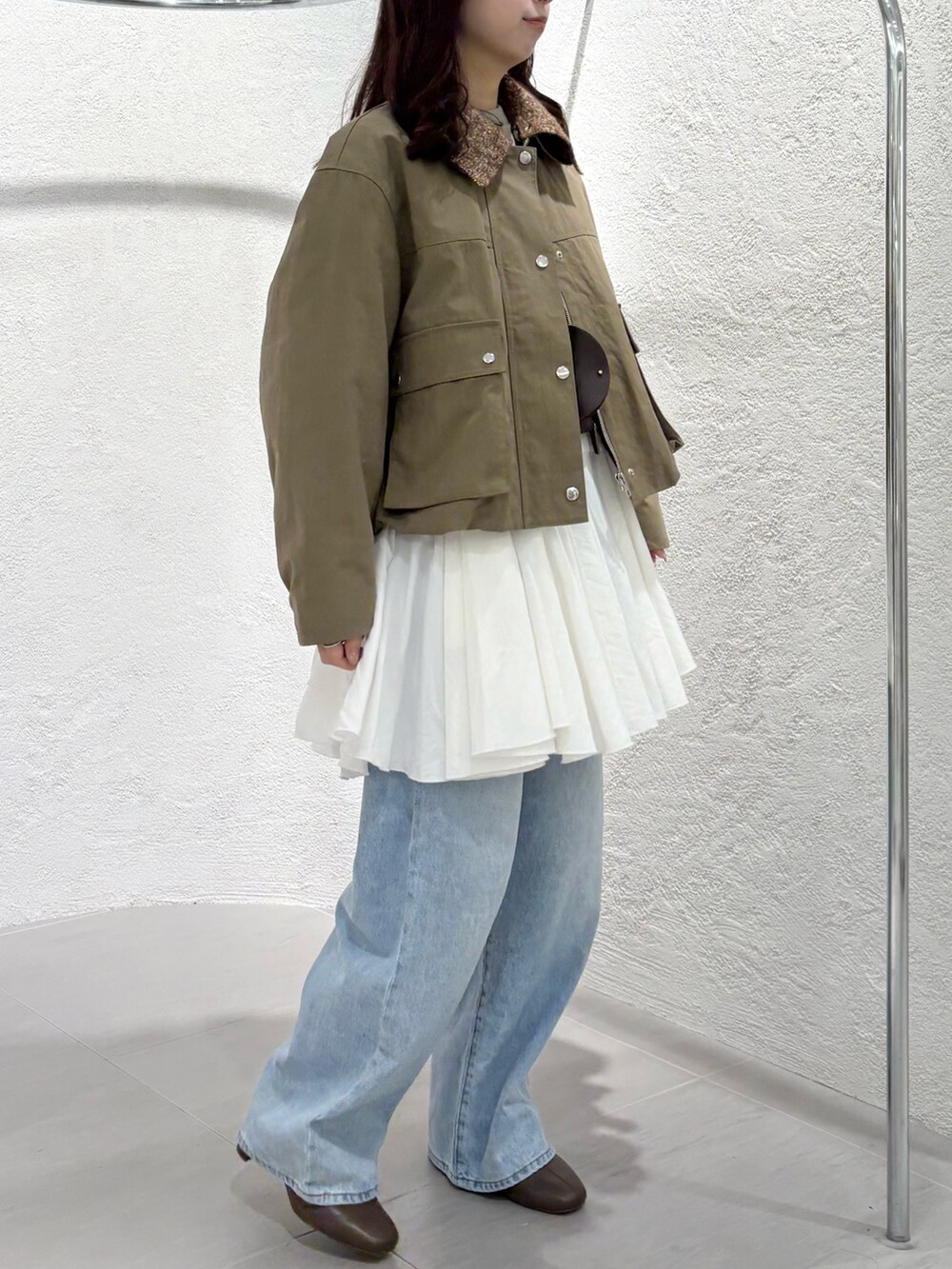 ブラウン系のショルダーバッグ、ベージュ系のスウェット、ホワイト系のワンピースを着用したレディースの冬コーディネートの2枚目の写真