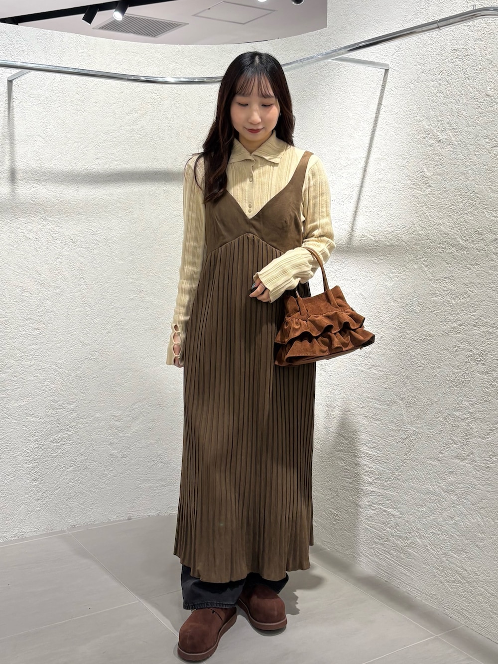 ブラウン系のワンピース、ベージュ系のニット/セーター、ブラック系のデニムパンツを着用したレディースの冬コーディネートの2枚目の写真