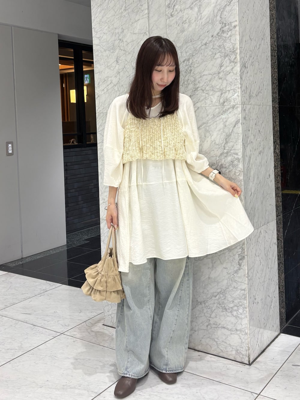 ホワイト系のワンピース、ホワイト系のニット/セーター、ブルー系のデニムパンツを着用したレディースの春コーディネートの2枚目の写真