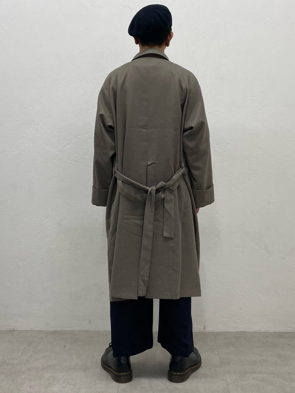 ベージュ系のステンカラーコート、ブルー系のスラックス、ブラック系のドレスシューズを着用したメンズの秋コーディネートの4枚目の写真