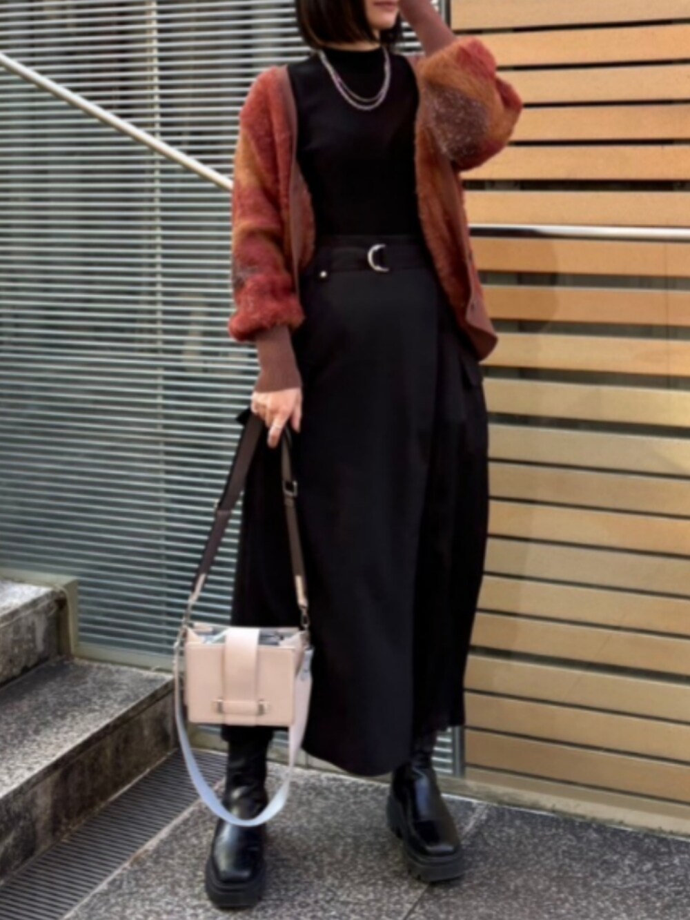 ホワイト系のショルダーバッグ、ブラウン系のカーディガン/ボレロ、ブラック系のスカートを着用したレディースの冬コーディネートの2枚目の写真