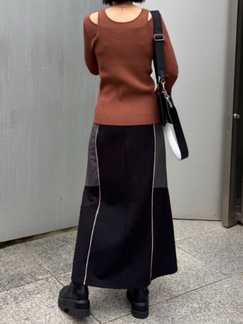 ブラック系のスカート、ブラック系のショルダーバッグ、イエロー系のニット/セーターを着用したレディースの秋コーディネートの3枚目の写真