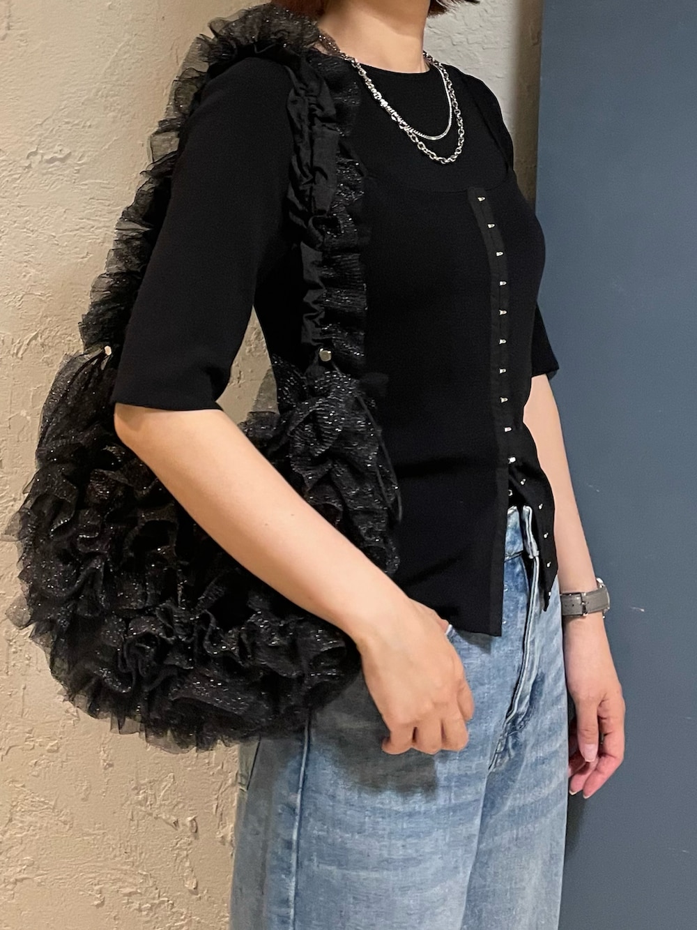 ブラック系のショルダーバッグ、ブラック系のニット/セーター、ホワイト系のサンダルを着用したレディースの冬コーディネートの2枚目の写真