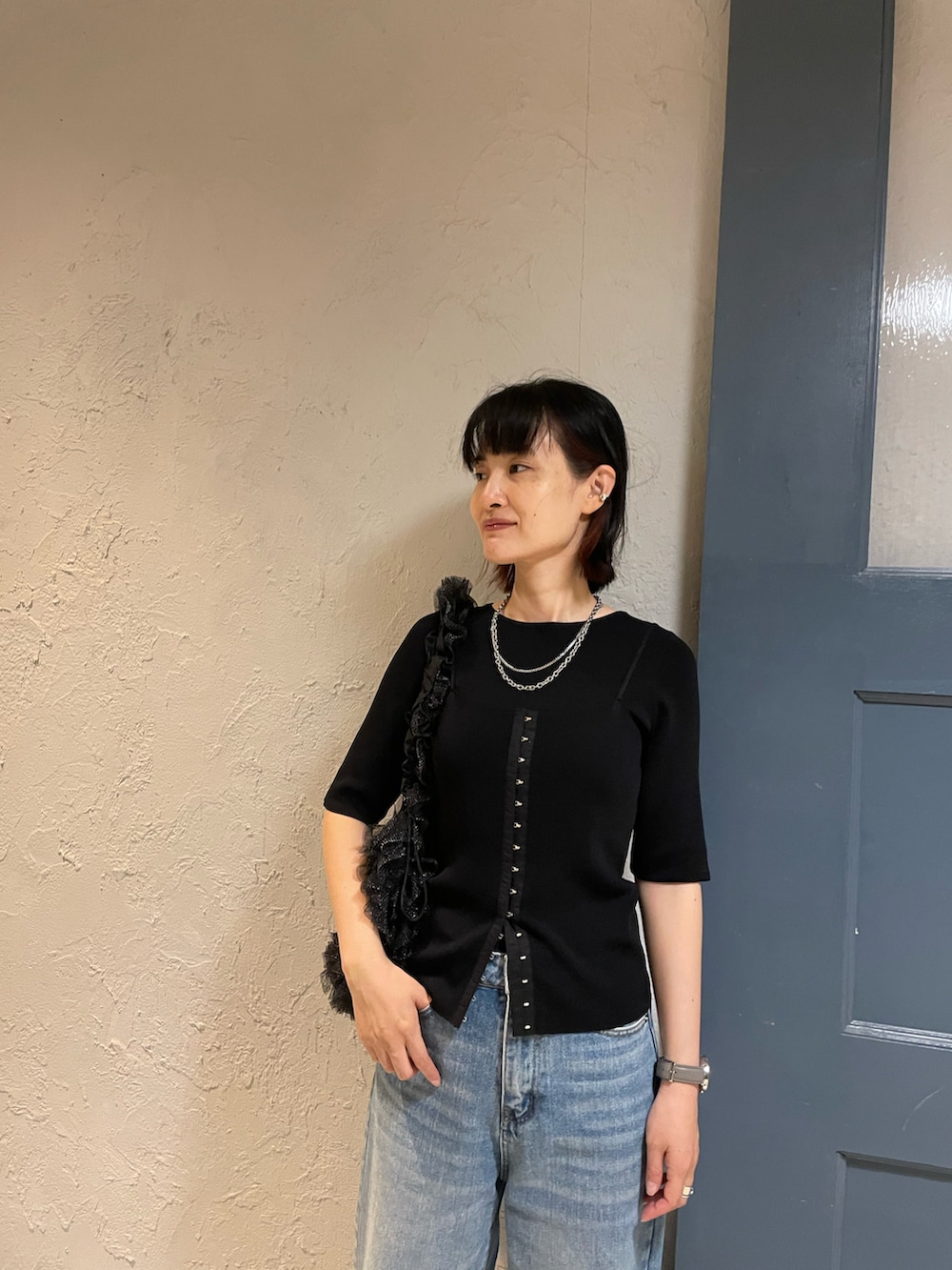 ブラック系のショルダーバッグ、ブラック系のニット/セーター、ホワイト系のサンダルを着用したレディースの冬コーディネートの3枚目の写真