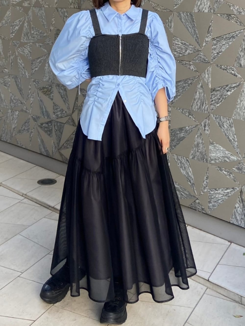 ブラック系のスカート、ブラック系のカーディガン/ボレロ、ブルー系のシャツ/ブラウスを着用したレディースの春コーディネートの2枚目の写真