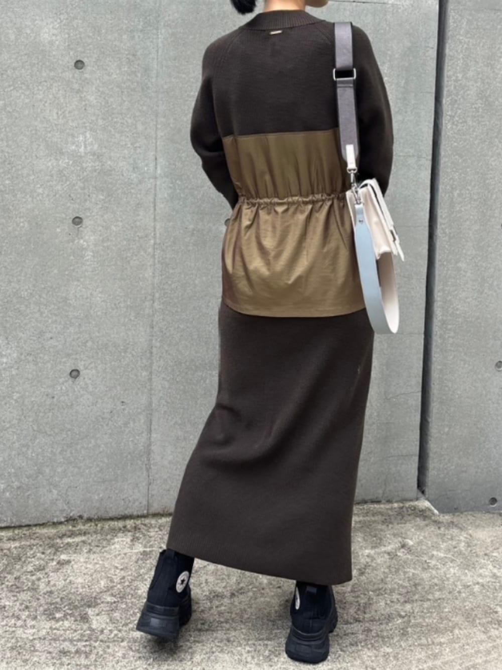 ブラック系のスニーカー、ホワイト系のショルダーバッグ、グリーン系のワンピースを着用したレディースの秋コーディネートの2枚目の写真