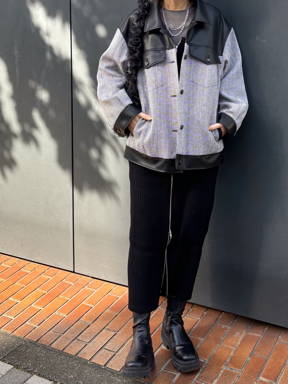 ブラック系のショルダーバッグ、その他のライダースジャケット、ブラック系のジャンパースカートを着用したレディースの冬コーディネートの2枚目の写真