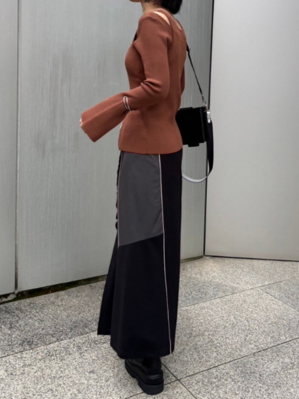 ブラック系のスカート、ブラック系のショルダーバッグ、イエロー系のニット/セーターを着用したレディースの秋コーディネートの2枚目の写真