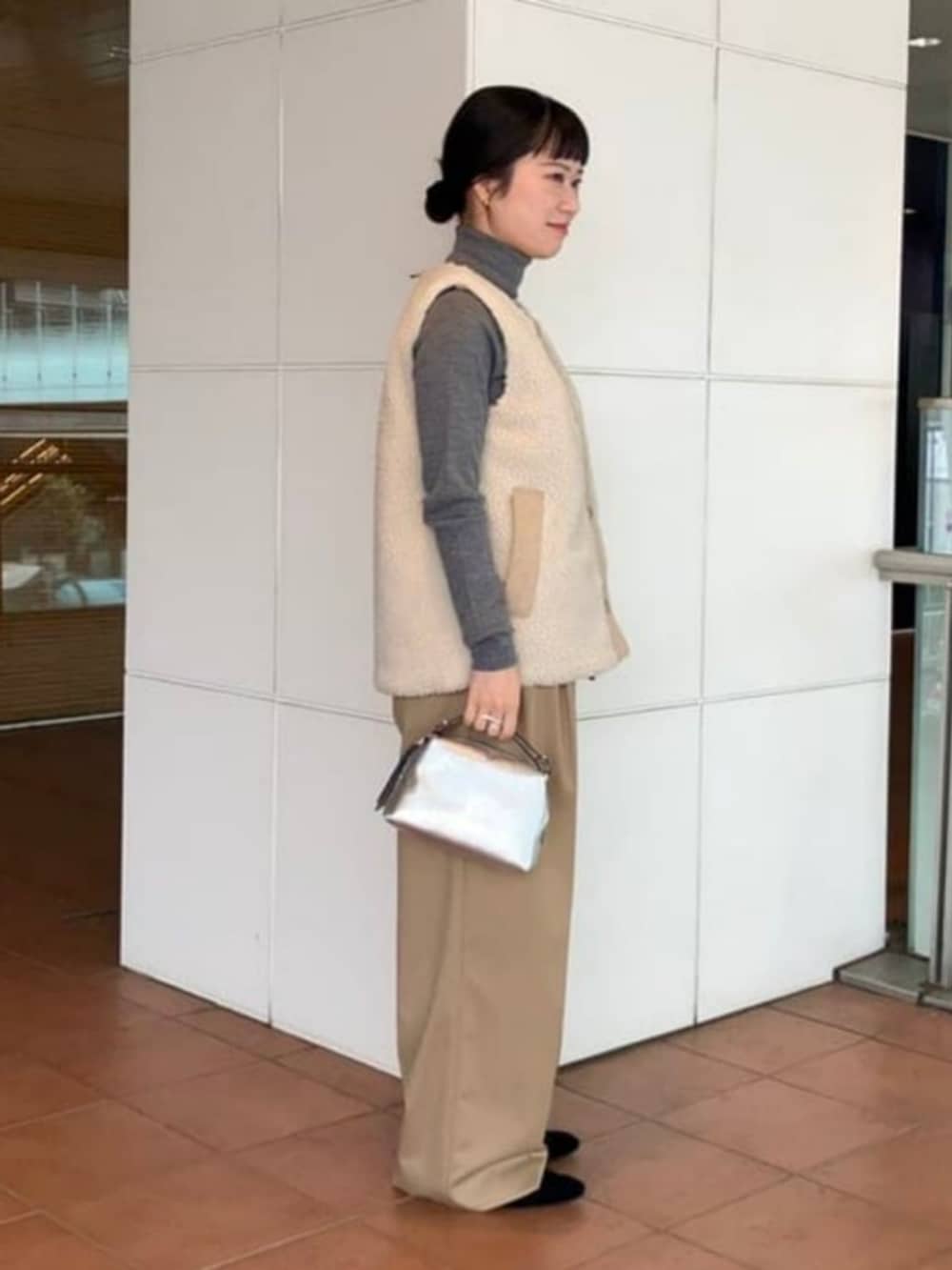 ブラウン系のニット/セーター、ベージュ系のその他パンツ、ホワイト系のその他アウターを着用したレディースの秋コーディネートの2枚目の写真