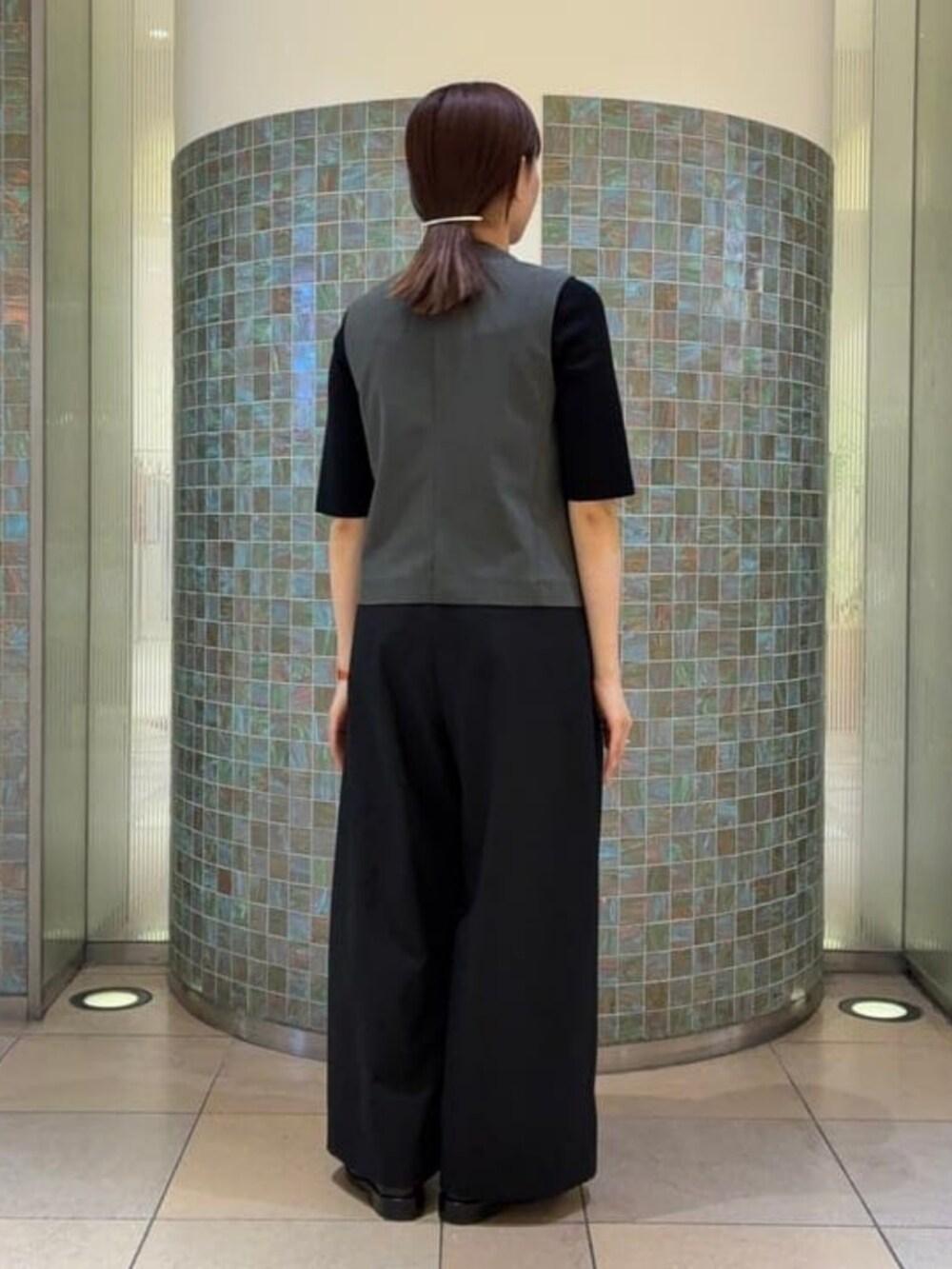 ブラック系のニット/セーター、ブラック系のスラックス、グレー系のベストを着用したレディースの夏コーディネートの3枚目の写真