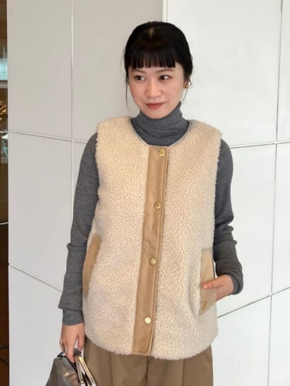 ブラウン系のニット/セーター、ベージュ系のその他パンツ、ホワイト系のその他アウターを着用したレディースの秋コーディネートの4枚目の写真