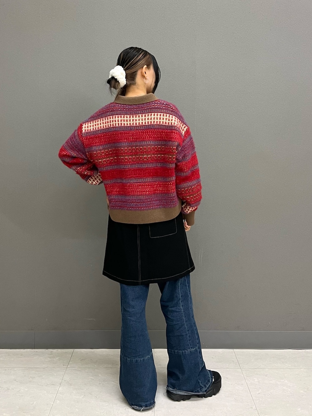 レッド系のニット/セーター、ブラック系のスカート、ブルー系のその他パンツを着用したレディースの冬コーディネートの4枚目の写真