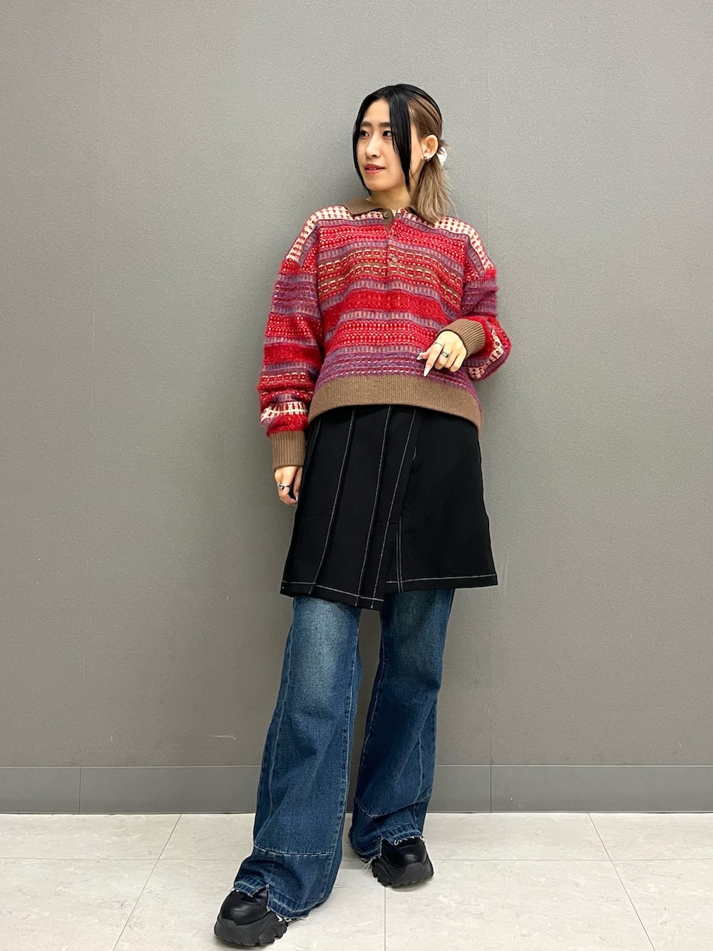 レッド系のニット/セーター、ブラック系のスカート、ブルー系のその他パンツを着用したレディースの冬コーディネートの3枚目の写真