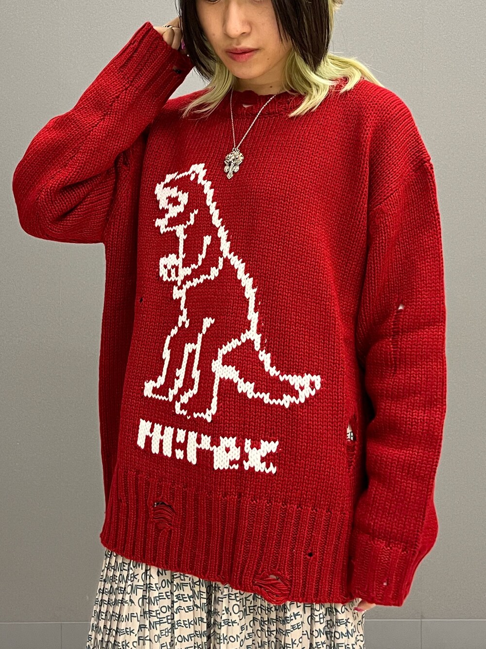 レッド系のニット/セーター、ホワイト系のTシャツ/カットソー、ベージュ系のスカートを着用したレディースの秋コーディネートの5枚目の写真