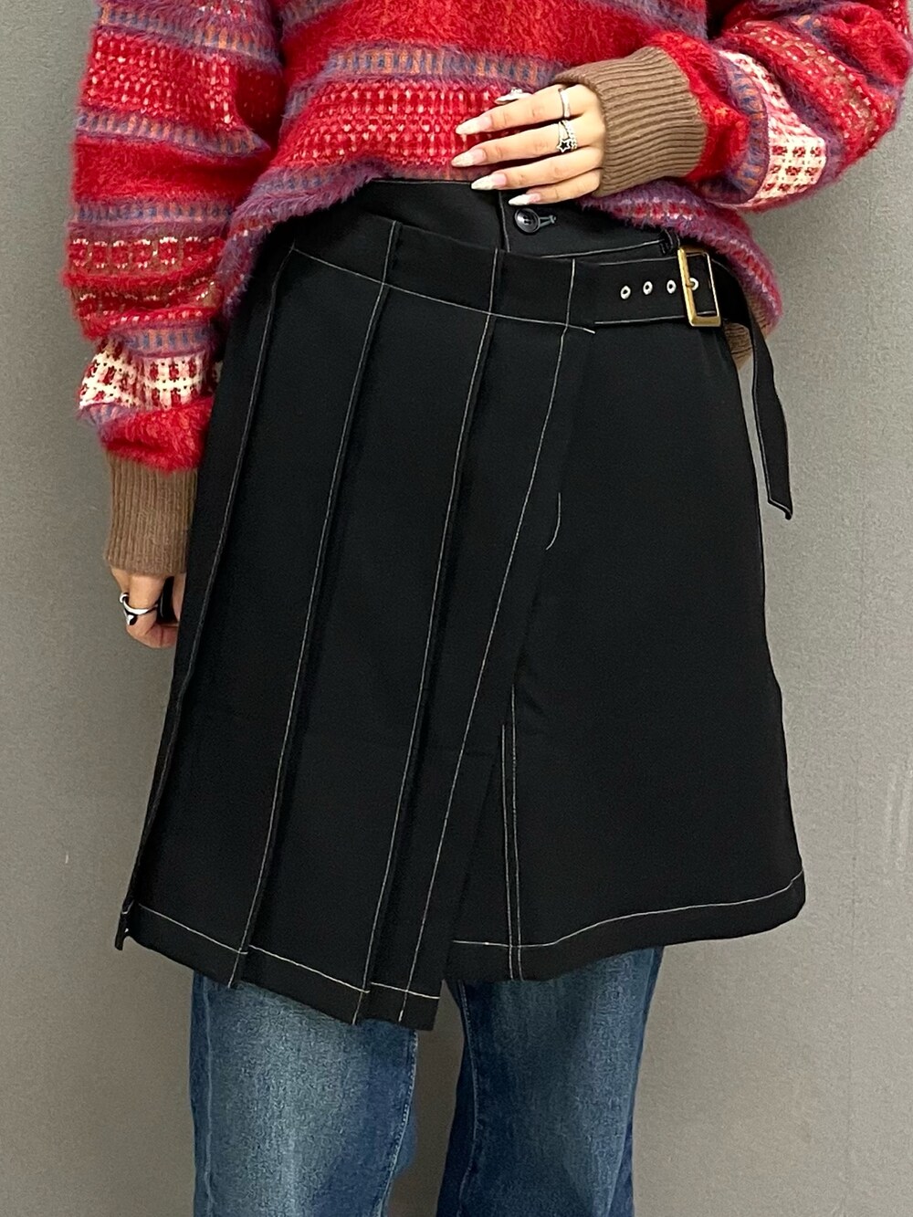 レッド系のニット/セーター、ブラック系のスカート、ブルー系のその他パンツを着用したレディースの冬コーディネートの6枚目の写真