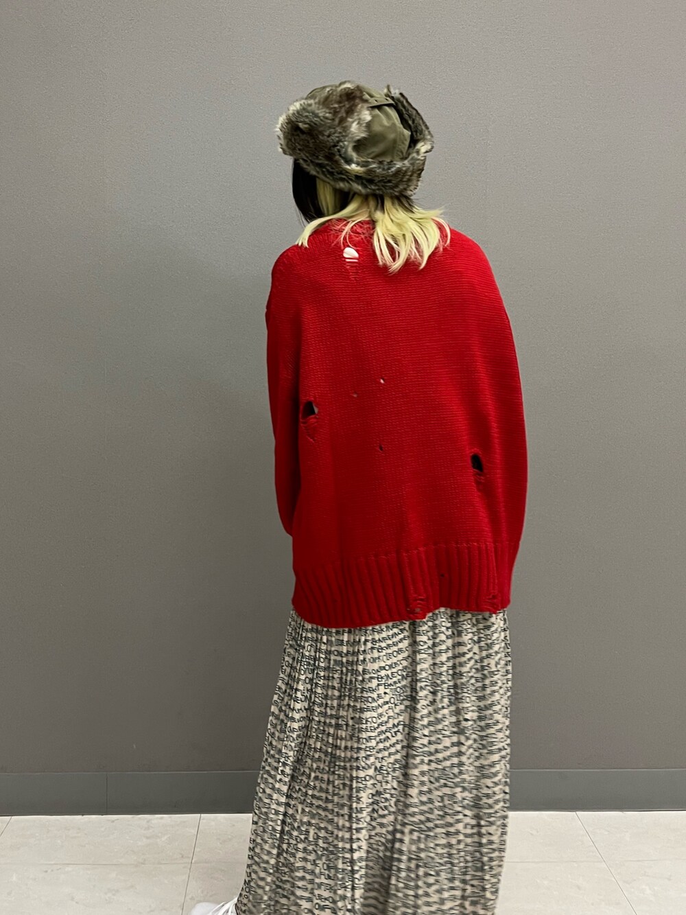 レッド系のニット/セーター、ホワイト系のTシャツ/カットソー、ベージュ系のスカートを着用したレディースの秋コーディネートの4枚目の写真