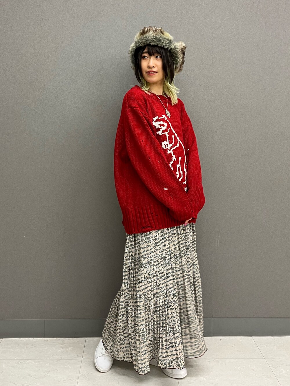 レッド系のニット/セーター、ホワイト系のTシャツ/カットソー、ベージュ系のスカートを着用したレディースの秋コーディネートの3枚目の写真