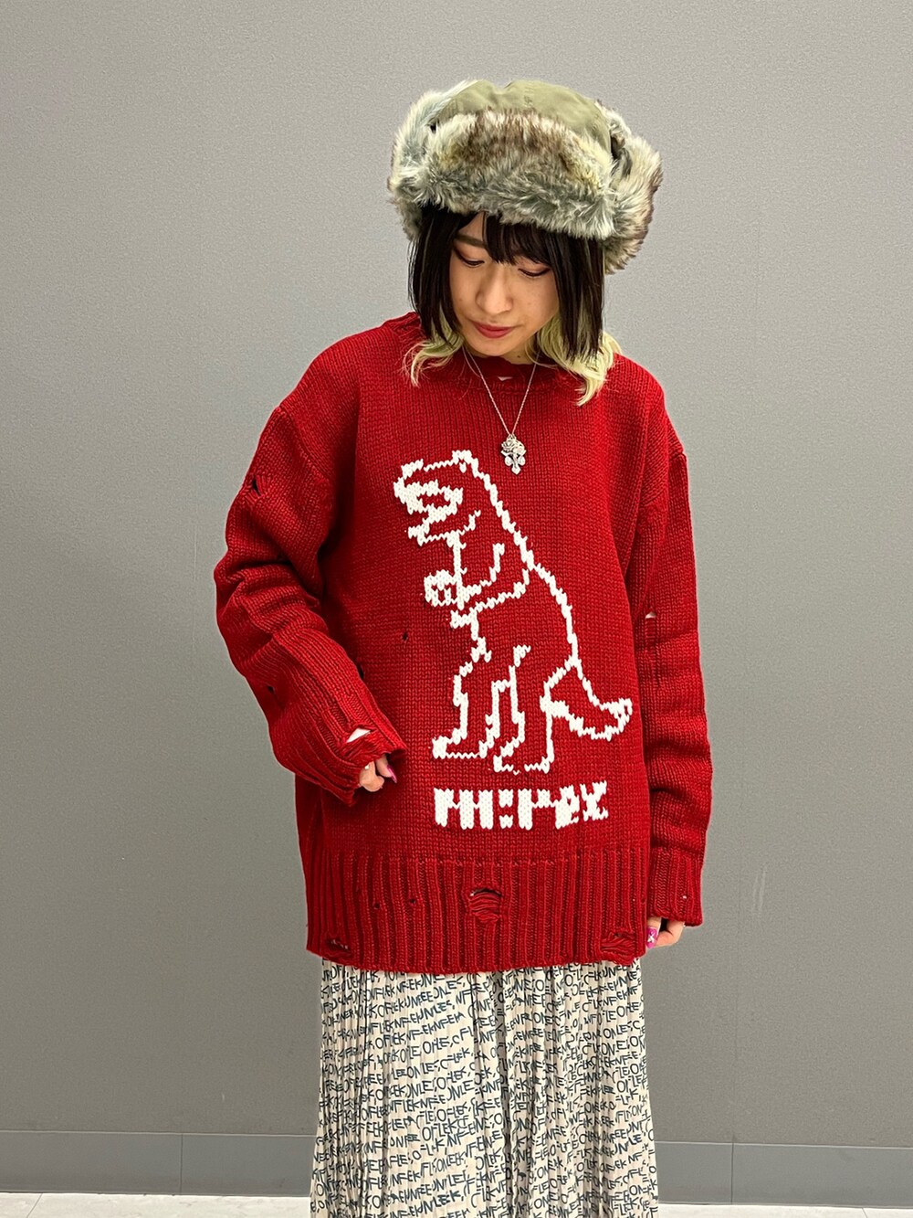 レッド系のニット/セーター、ホワイト系のTシャツ/カットソー、ベージュ系のスカートを着用したレディースの秋コーディネートの6枚目の写真