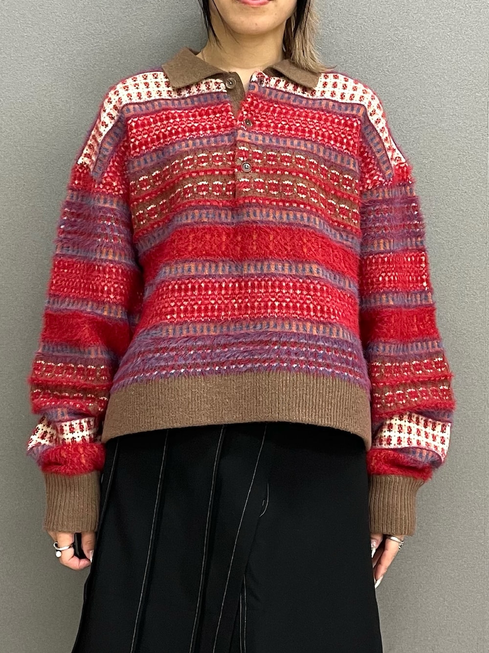 レッド系のニット/セーター、ブラック系のスカート、ブルー系のその他パンツを着用したレディースの冬コーディネートの5枚目の写真