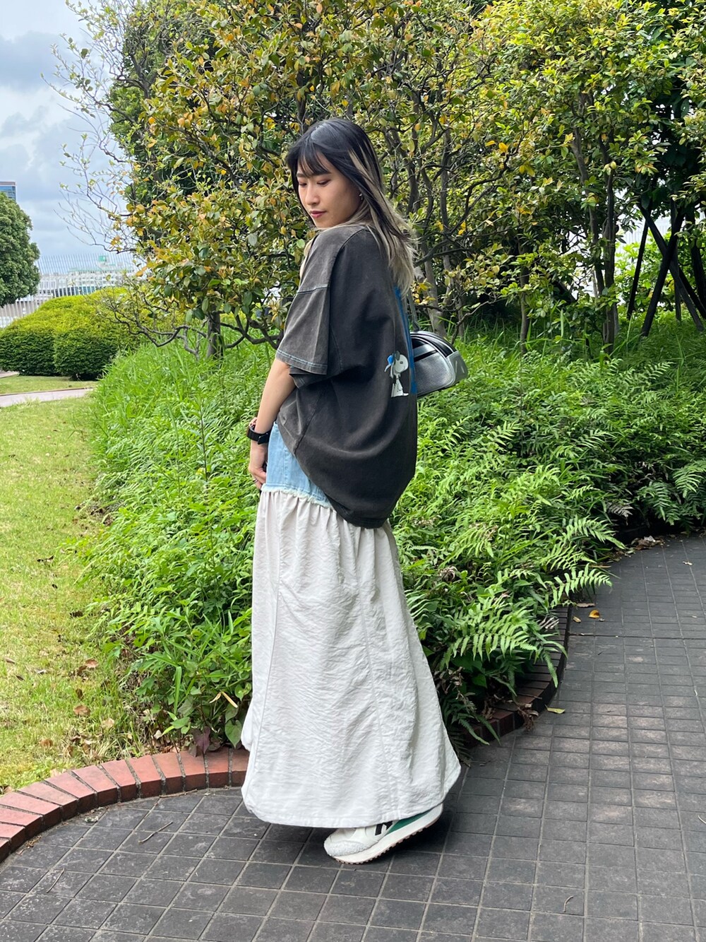 ホワイト系のスカート、ブラック系のTシャツ/カットソー、シルバー系のハンドバッグを着用したレディースの夏コーディネートの2枚目の写真