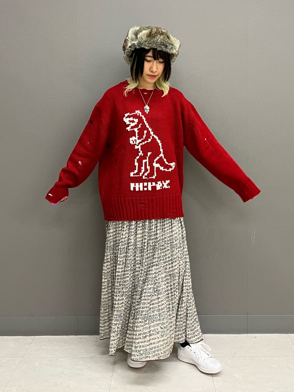 レッド系のニット/セーター、ホワイト系のTシャツ/カットソー、ベージュ系のスカートを着用したレディースの秋コーディネートの2枚目の写真