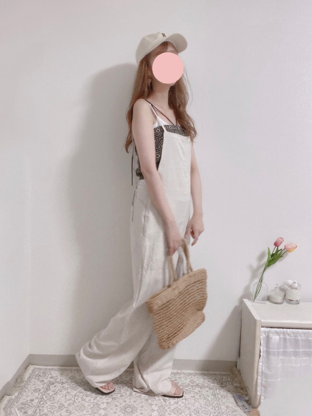 ホワイト系のオールインワン・サロペット、ベージュ系のかごバッグ、ブラック系のキャミソールを着用したレディースの夏コーディネートの2枚目の写真