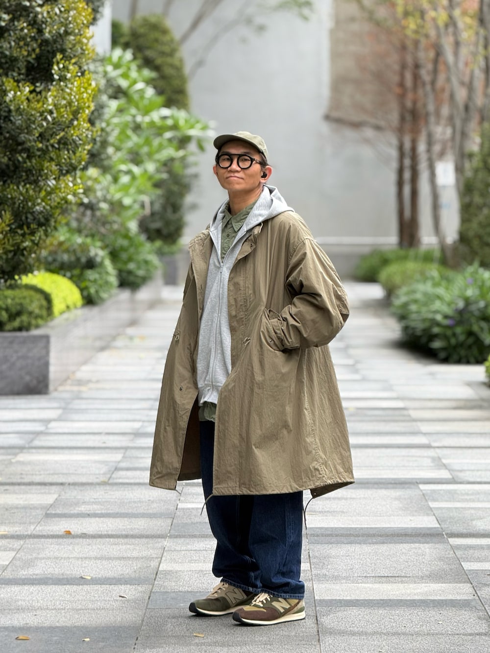 グレー系のスタジャン、グリーン系のミリタリージャケット、ブルー系のデニムパンツを着用したメンズの春コーディネートの2枚目の写真