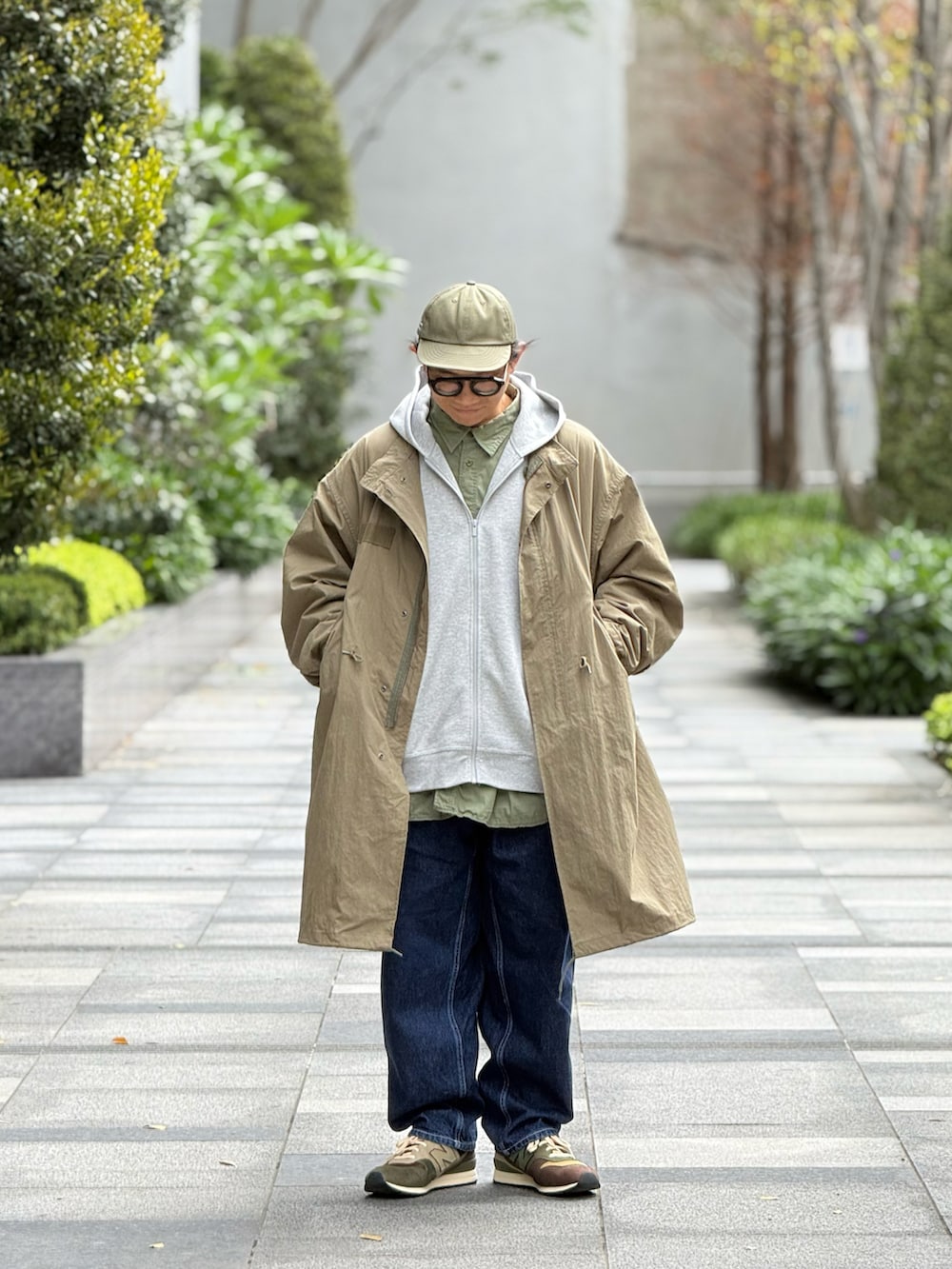 グレー系のスタジャン、グリーン系のミリタリージャケット、ブルー系のデニムパンツを着用したメンズの春コーディネートの4枚目の写真