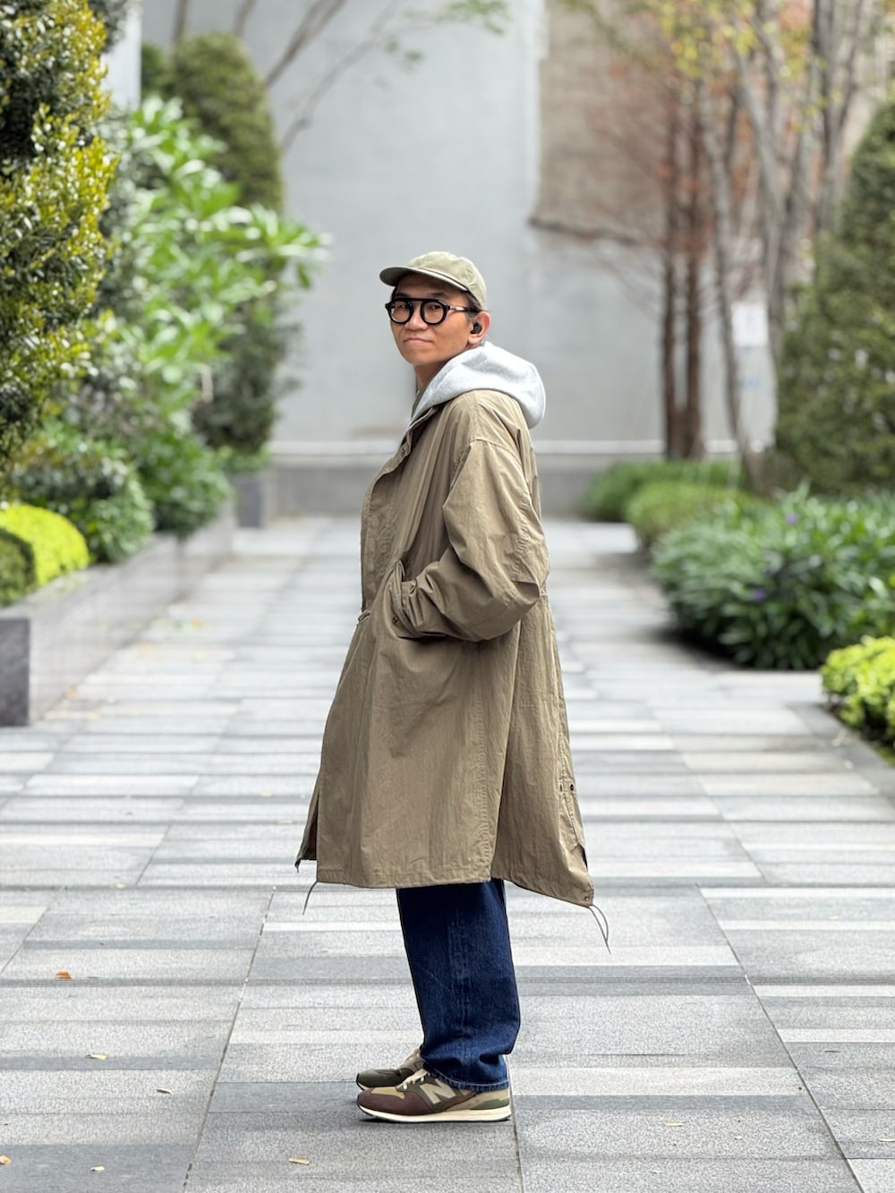 グレー系のスタジャン、グリーン系のミリタリージャケット、ブルー系のデニムパンツを着用したメンズの春コーディネートの3枚目の写真