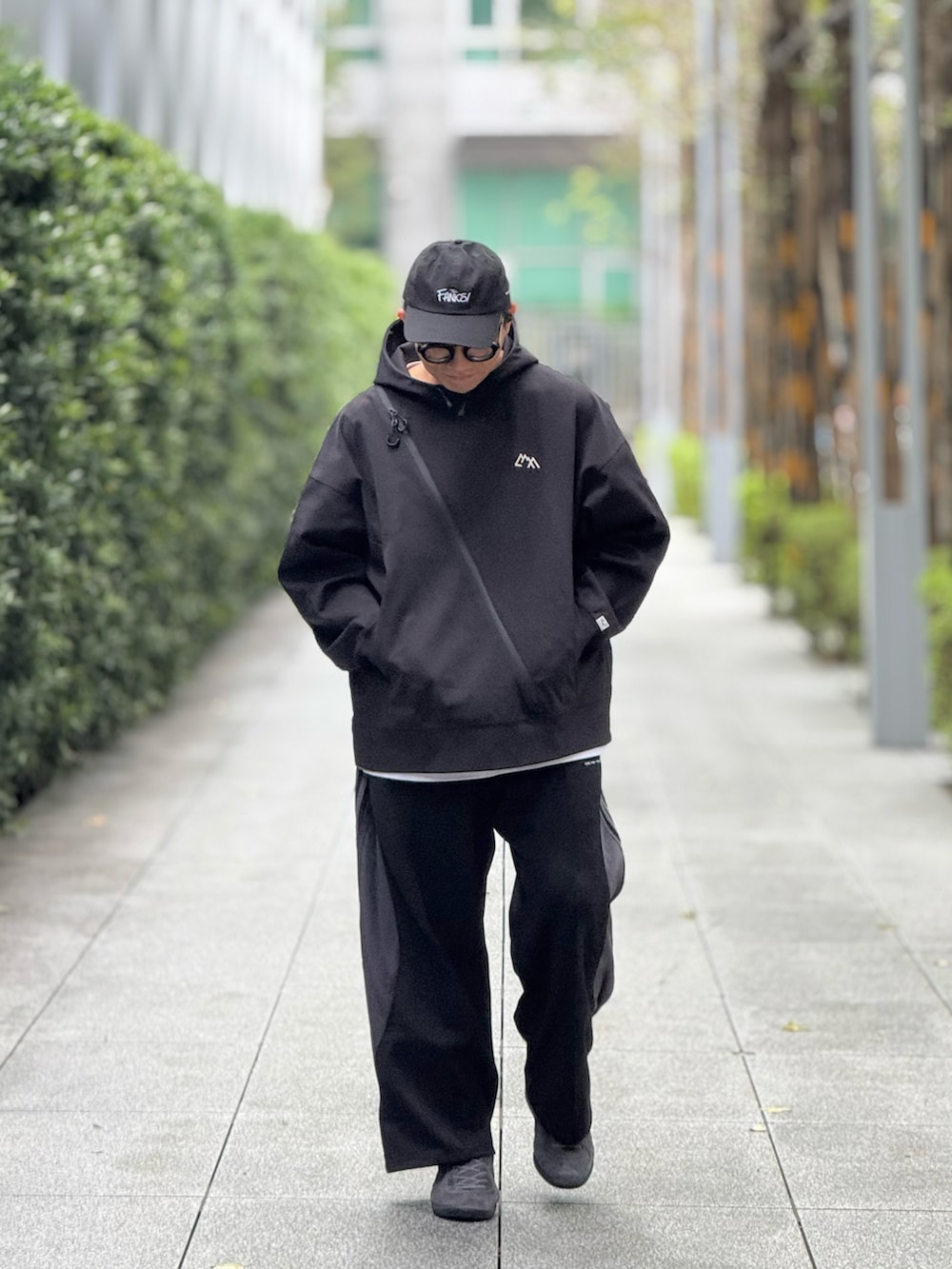 ブラック系のスウェット、ブラック系のチノパンツ、グレー系のスニーカーを着用したメンズの冬コーディネートの3枚目の写真