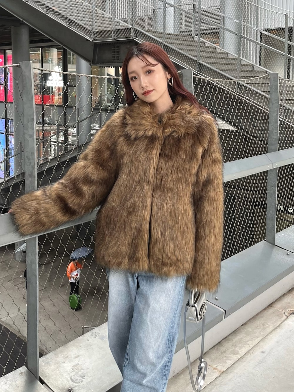 ブラウン系のその他アウター、ブルー系のデニムパンツ、シルバー系のショルダーバッグを着用したレディースの冬コーディネートの2枚目の写真