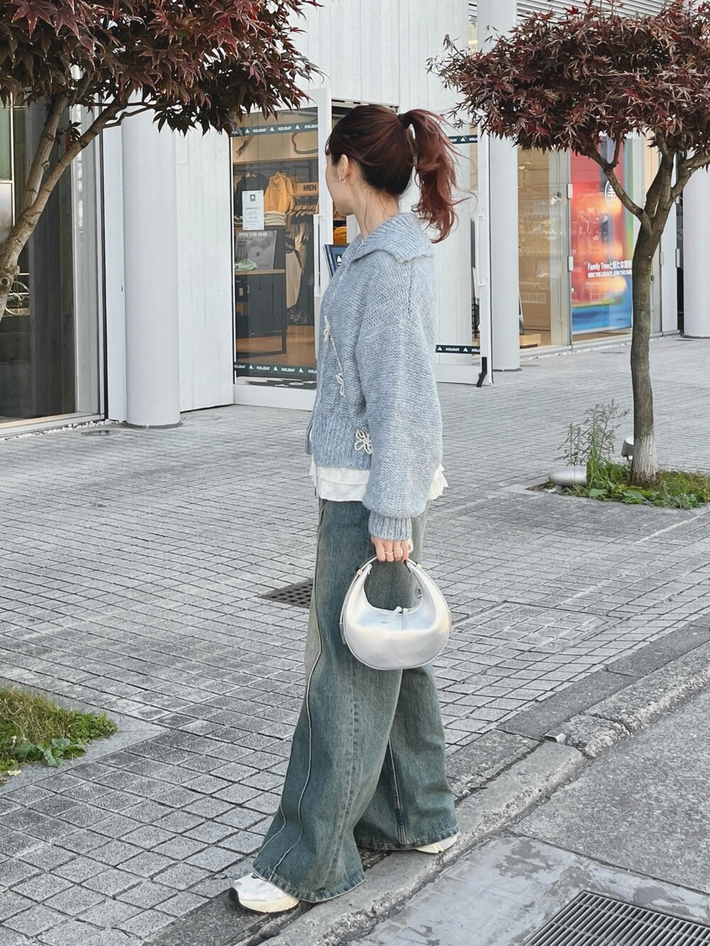 ブルー系のニット/セーター、ブルー系のデニムパンツ、ホワイト系のスニーカーを着用したレディースの春コーディネートの2枚目の写真