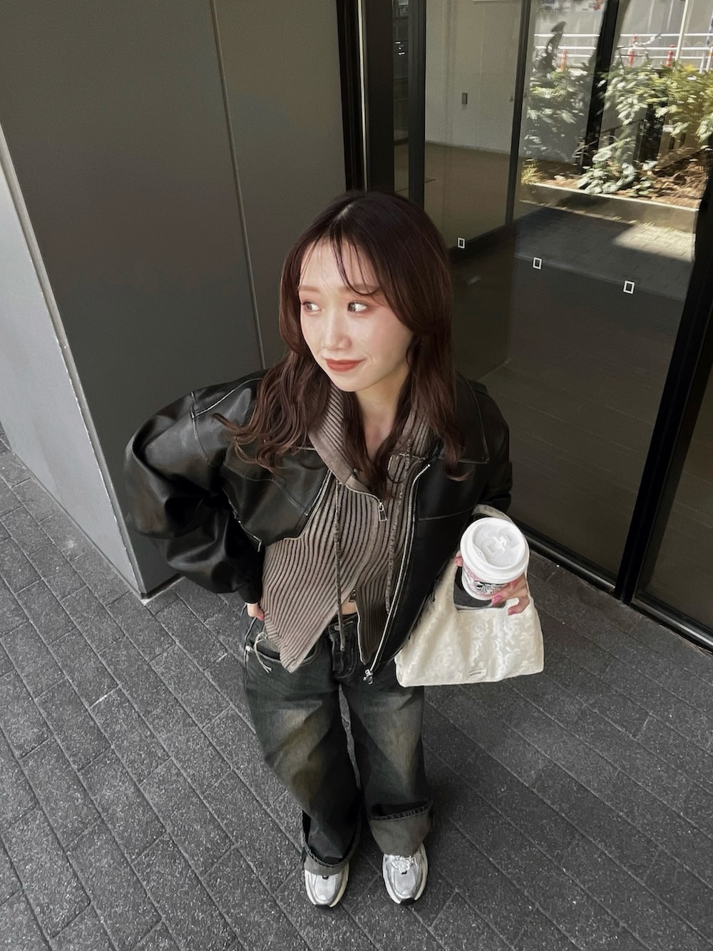 ブラック系のブルゾン、ブルー系のデニムパンツ、ホワイト系のスニーカーを着用したレディースの秋コーディネートの3枚目の写真