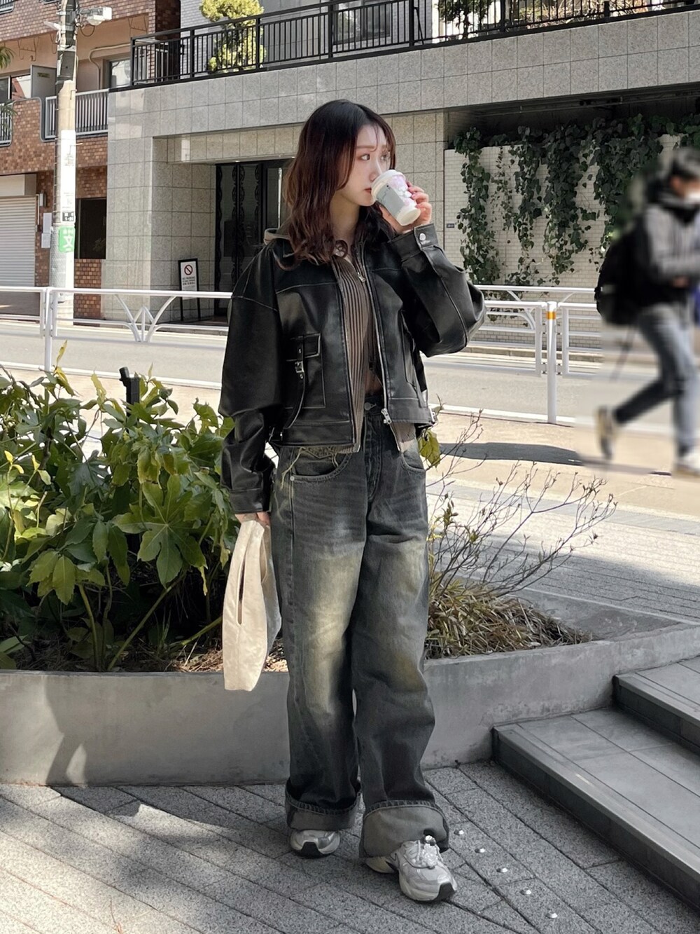 ブラック系のブルゾン、ブルー系のデニムパンツ、ホワイト系のスニーカーを着用したレディースの秋コーディネートの2枚目の写真