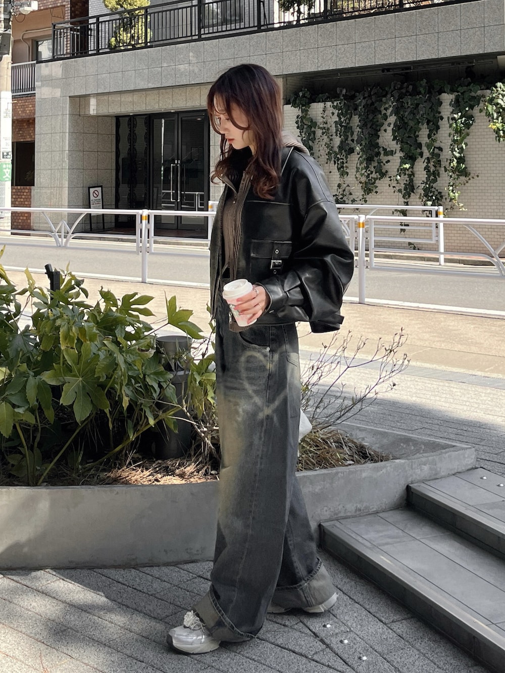 ブラック系のブルゾン、ブルー系のデニムパンツ、ホワイト系のスニーカーを着用したレディースの秋コーディネートの4枚目の写真