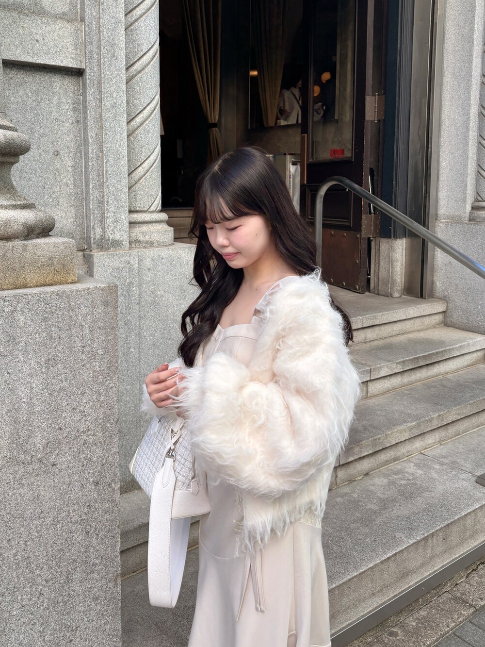 ホワイト系のショルダーバッグ、ホワイト系のカーディガン/ボレロ、ホワイト系のワンピース/ドレスを着用したレディースの冬コーディネートの3枚目の写真