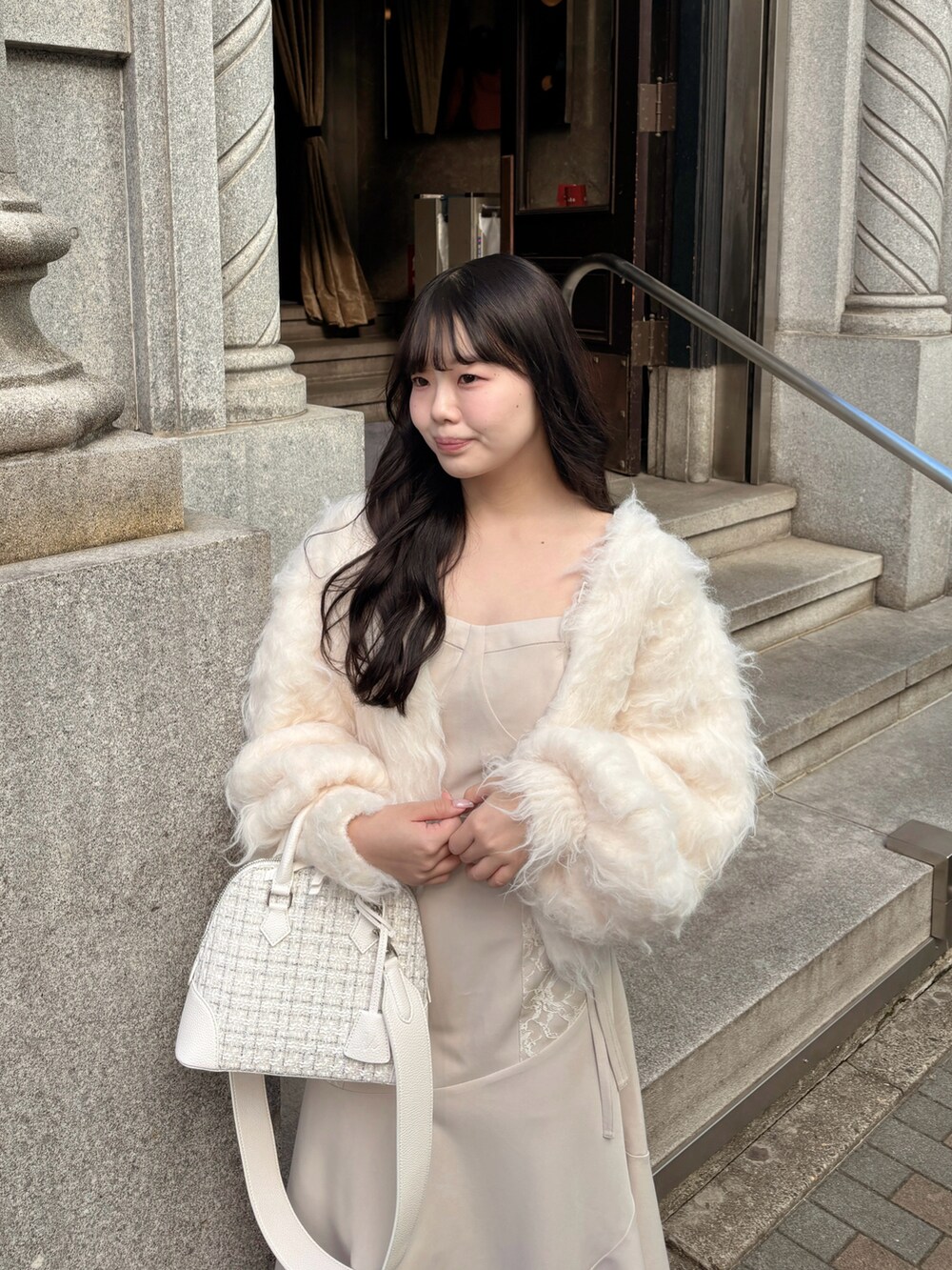 ホワイト系のショルダーバッグ、ホワイト系のカーディガン/ボレロ、ホワイト系のワンピース/ドレスを着用したレディースの冬コーディネートの4枚目の写真