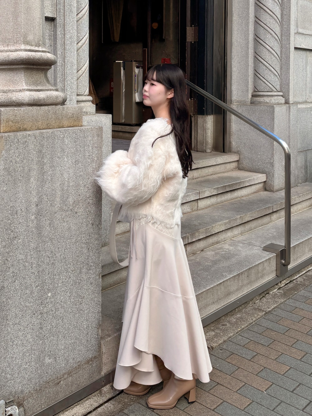 ホワイト系のショルダーバッグ、ホワイト系のカーディガン/ボレロ、ホワイト系のワンピース/ドレスを着用したレディースの冬コーディネートの2枚目の写真