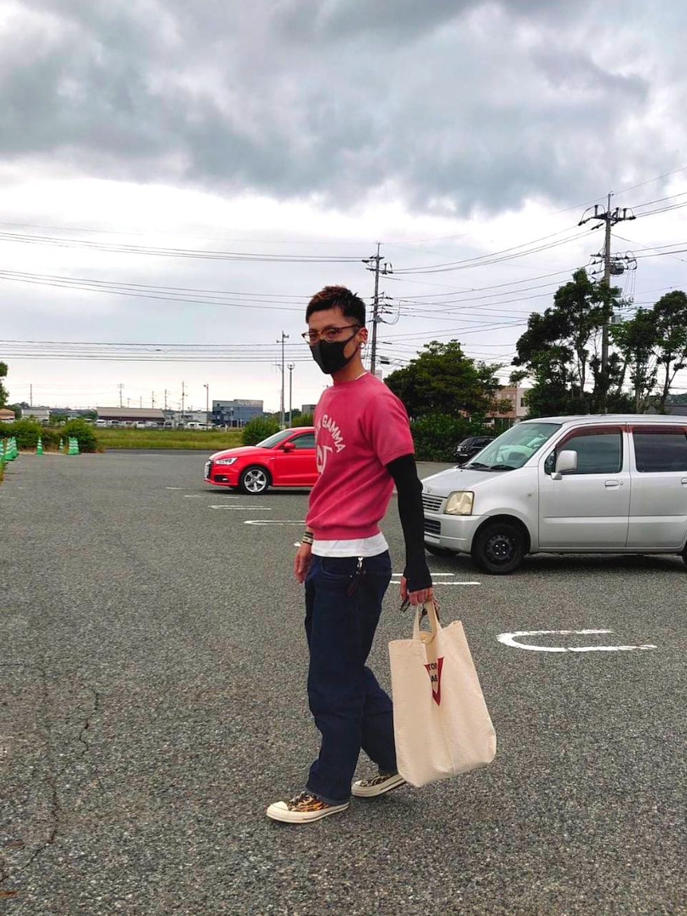 レッド系のTシャツ/カットソー、ブルー系のデニムパンツ、オレンジ系のスニーカーを着用したメンズの夏コーディネートの2枚目の写真