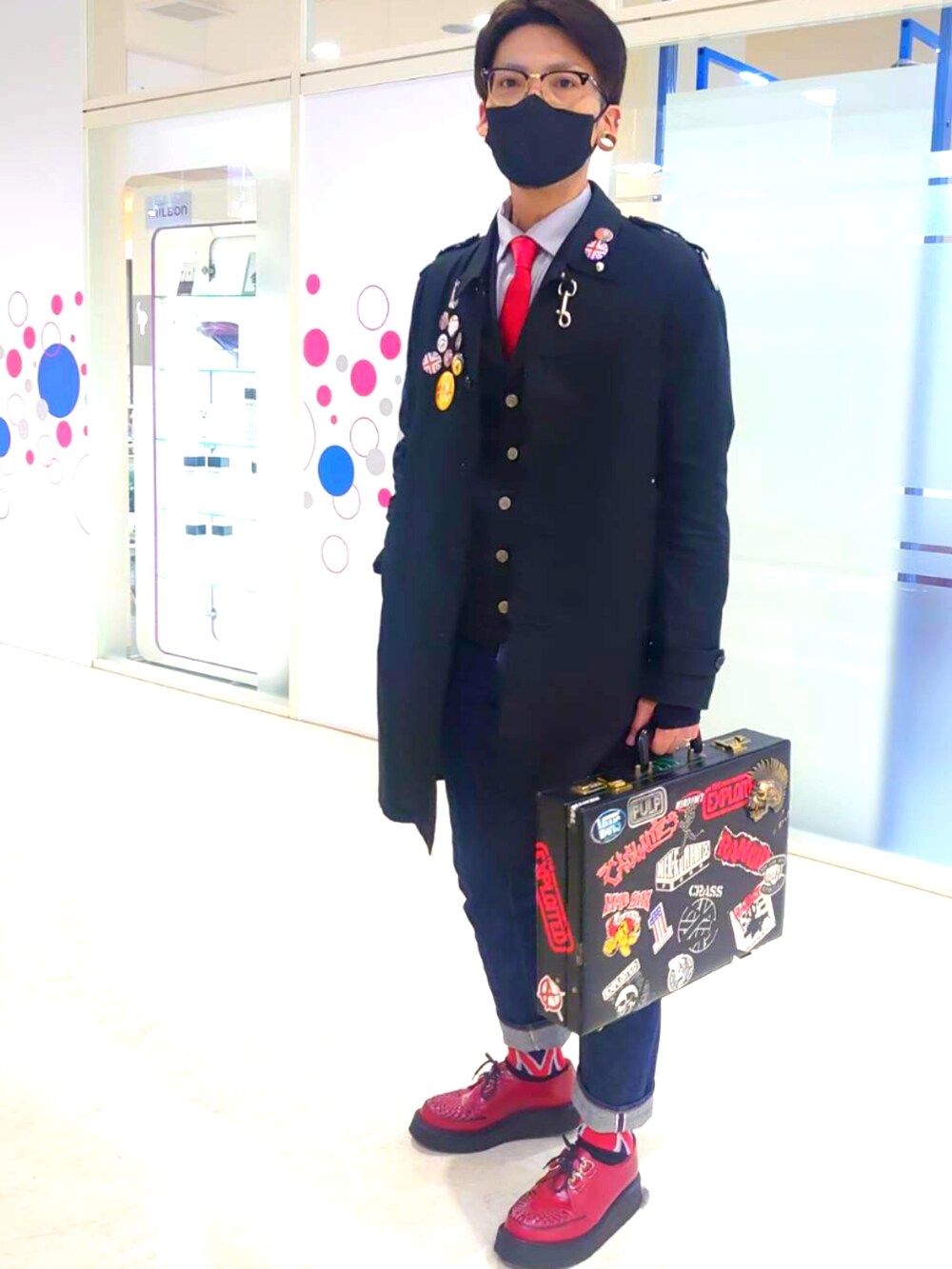 レッド系のネクタイ、ブラック系のミリタリージャケット、ブルー系のデニムパンツを着用したメンズの冬コーディネートの3枚目の写真