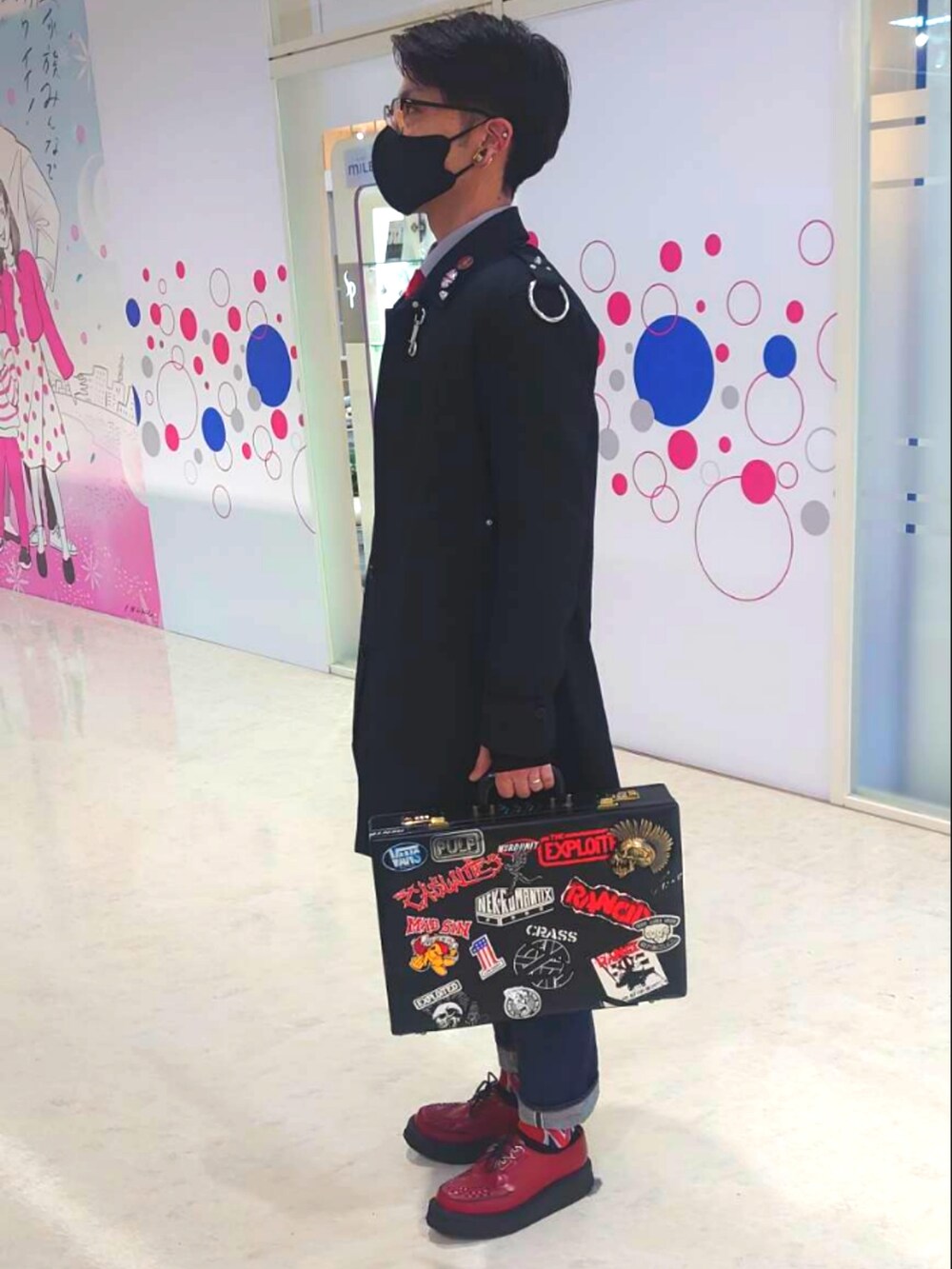 レッド系のネクタイ、ブラック系のミリタリージャケット、ブルー系のデニムパンツを着用したメンズの冬コーディネートの2枚目の写真