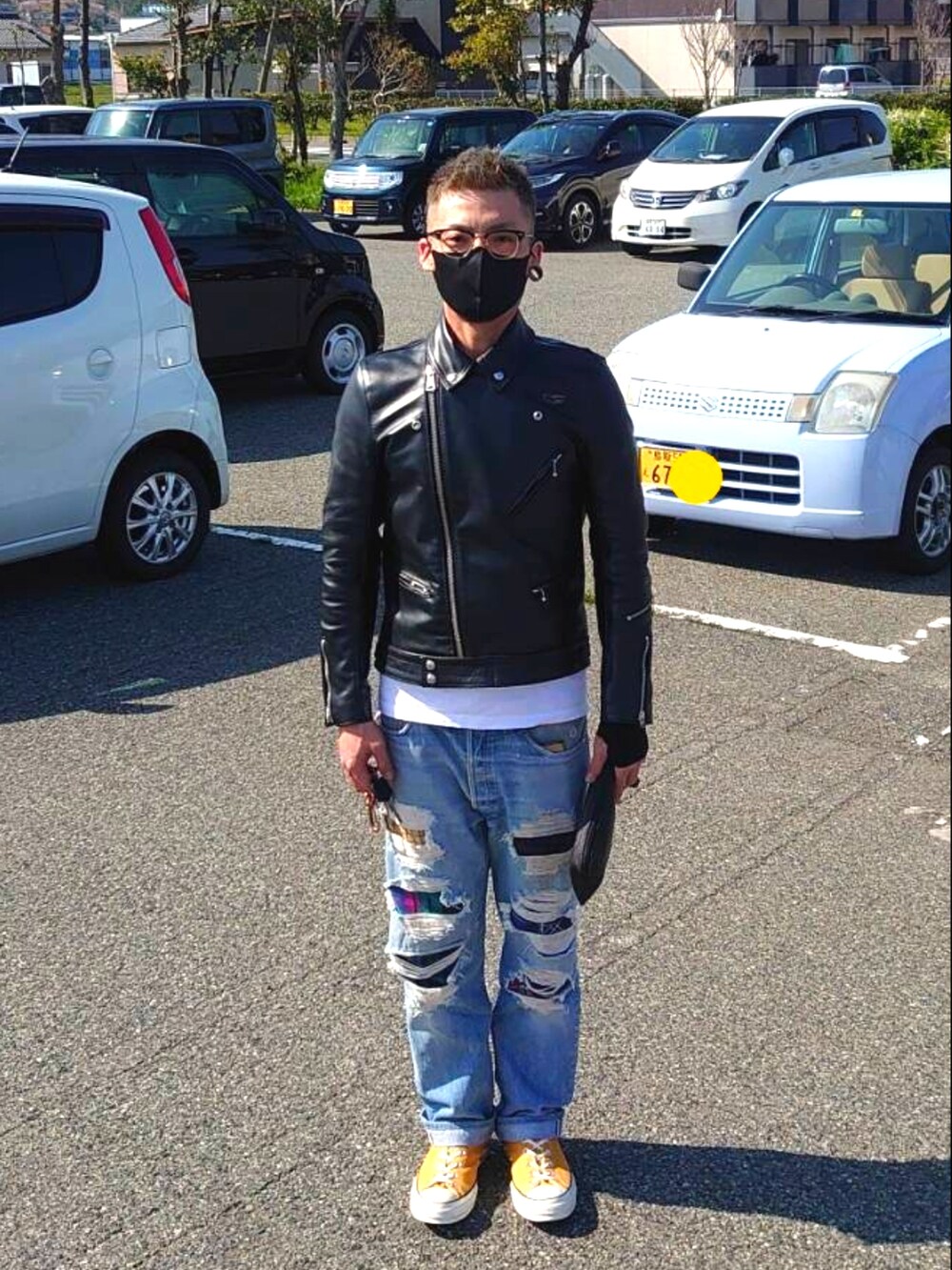 ブラック系のライダースジャケット、ブルー系のデニムパンツ、イエロー系のスニーカーを着用したメンズの春コーディネートの2枚目の写真