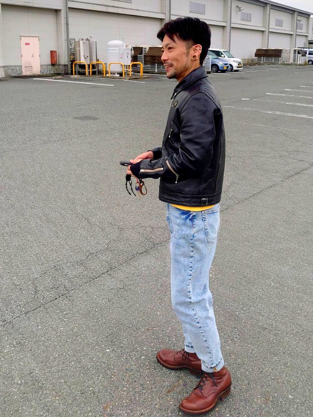 ブルー系のデニムパンツ、ブラウン系のブーツ、ブラック系のライダースジャケットを着用したメンズの秋コーディネートの2枚目の写真