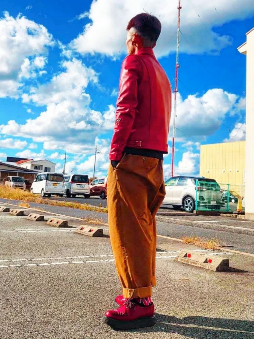 レッド系のライダースジャケット、ベージュ系のチノパンツ、レッド系のドレスシューズを着用したメンズの秋コーディネートの2枚目の写真