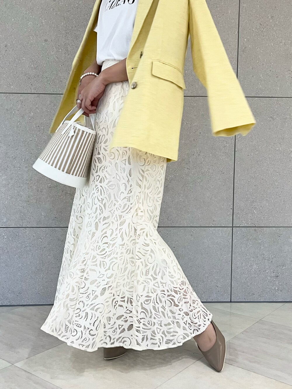 イエロー系のノーカラージャケット、ホワイト系のTシャツ/カットソー、ホワイト系のハンドバッグを着用したレディースの春コーディネートの5枚目の写真