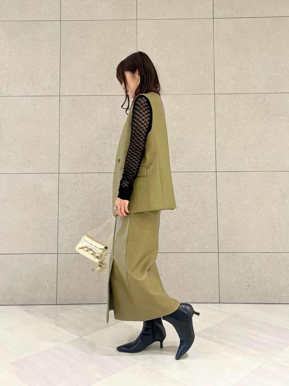 ブラック系のニット/セーター、グリーン系のベスト、グリーン系のスカートを着用したレディースの秋コーディネートの2枚目の写真