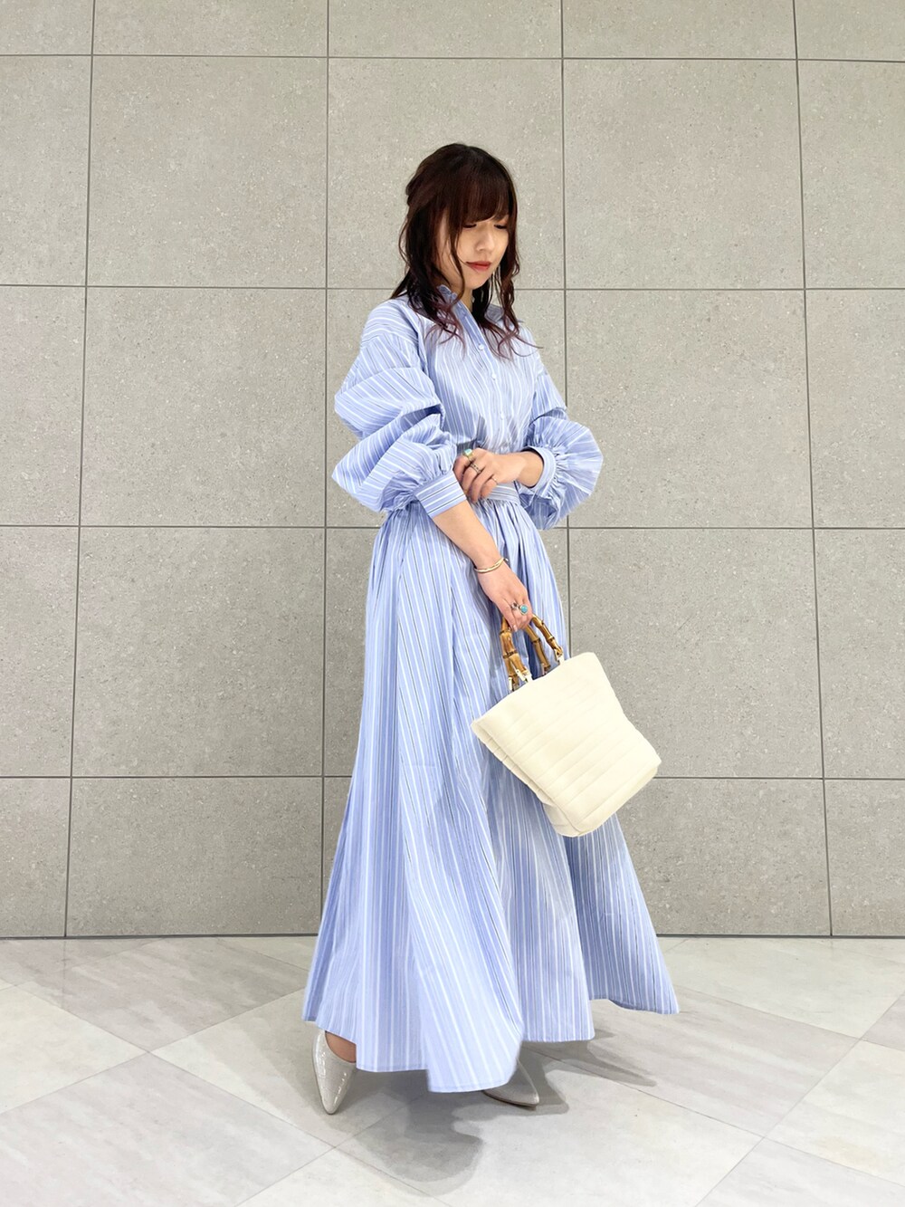 ブルー系のシャツ/ブラウス、ブルー系のスカート、ホワイト系のハンドバッグを着用したレディースの冬コーディネートの2枚目の写真