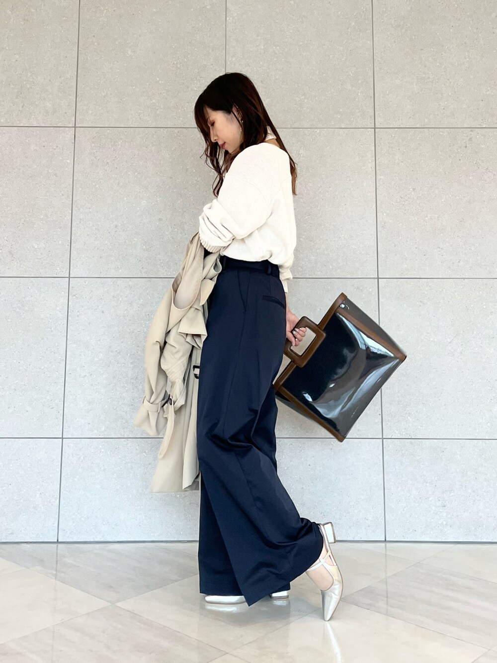 ベージュ系のトレンチコート、ホワイト系のニット/セーター、ブルー系のハンドバッグを着用したレディースの春コーディネートの4枚目の写真